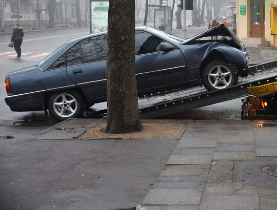 side angle of a crashed car being loaded onto a tow truck